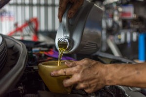 Mecânico realizando a troca do reservatório de fluido de um véiculo.